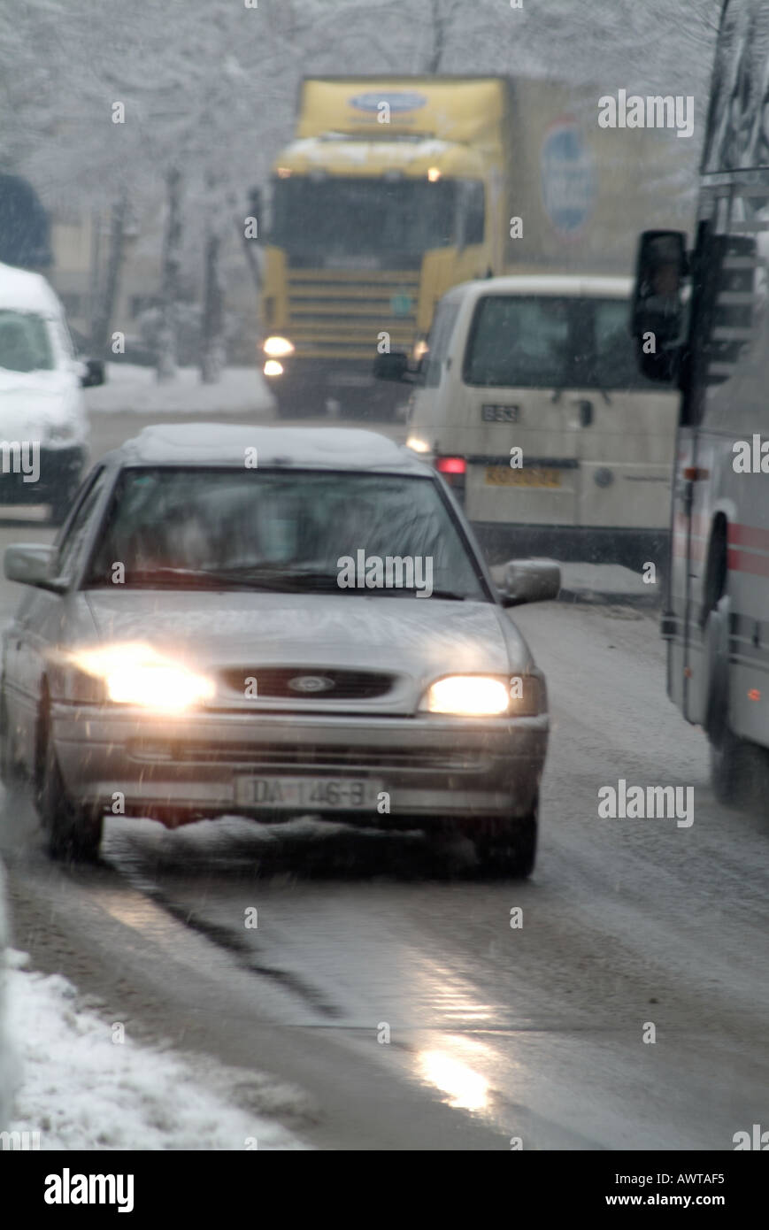 Fahrzeuge fahren auf Schnee und Eis bedeckt Europastraße im Winter Stockfoto