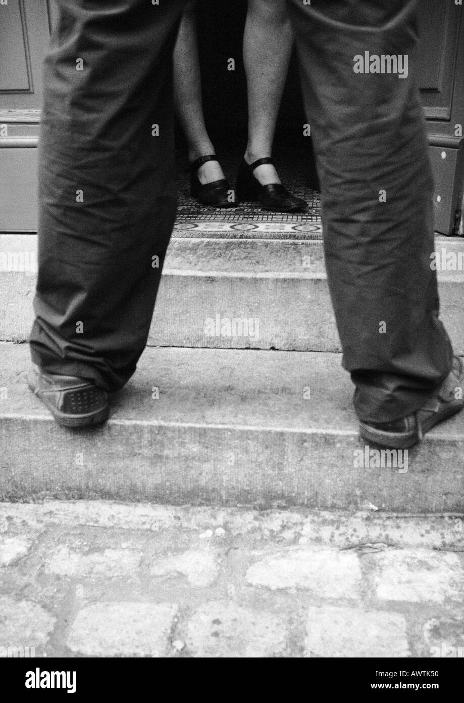 Frau in der Tür, Mann auf Treppe, niedrigen Bereich, b&w Stockfoto