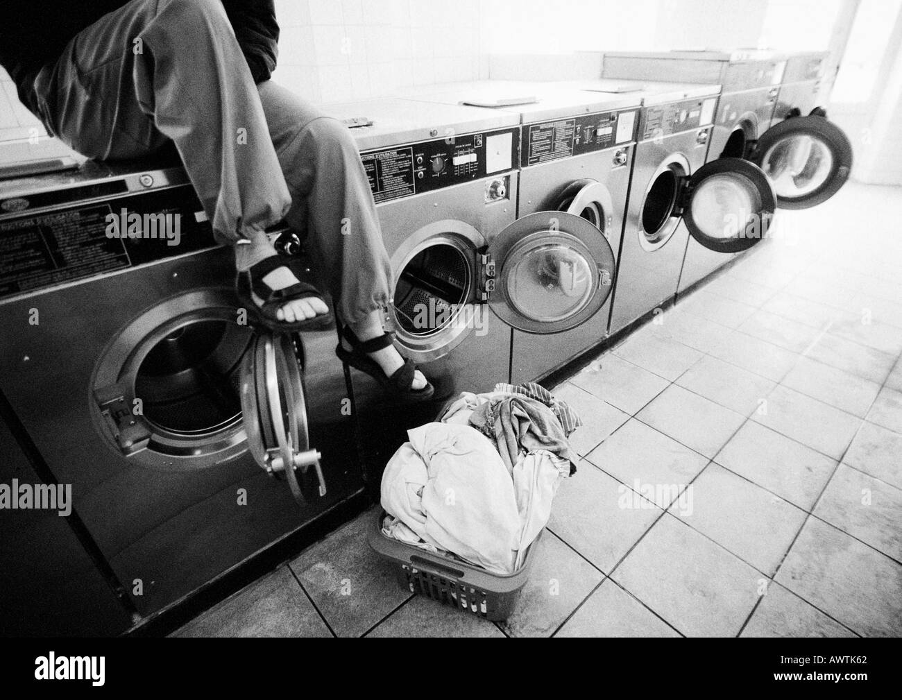 Sitzenden auf Waschmaschine im Waschsalon gesehen, niedrigen Bereich, b&w Stockfoto