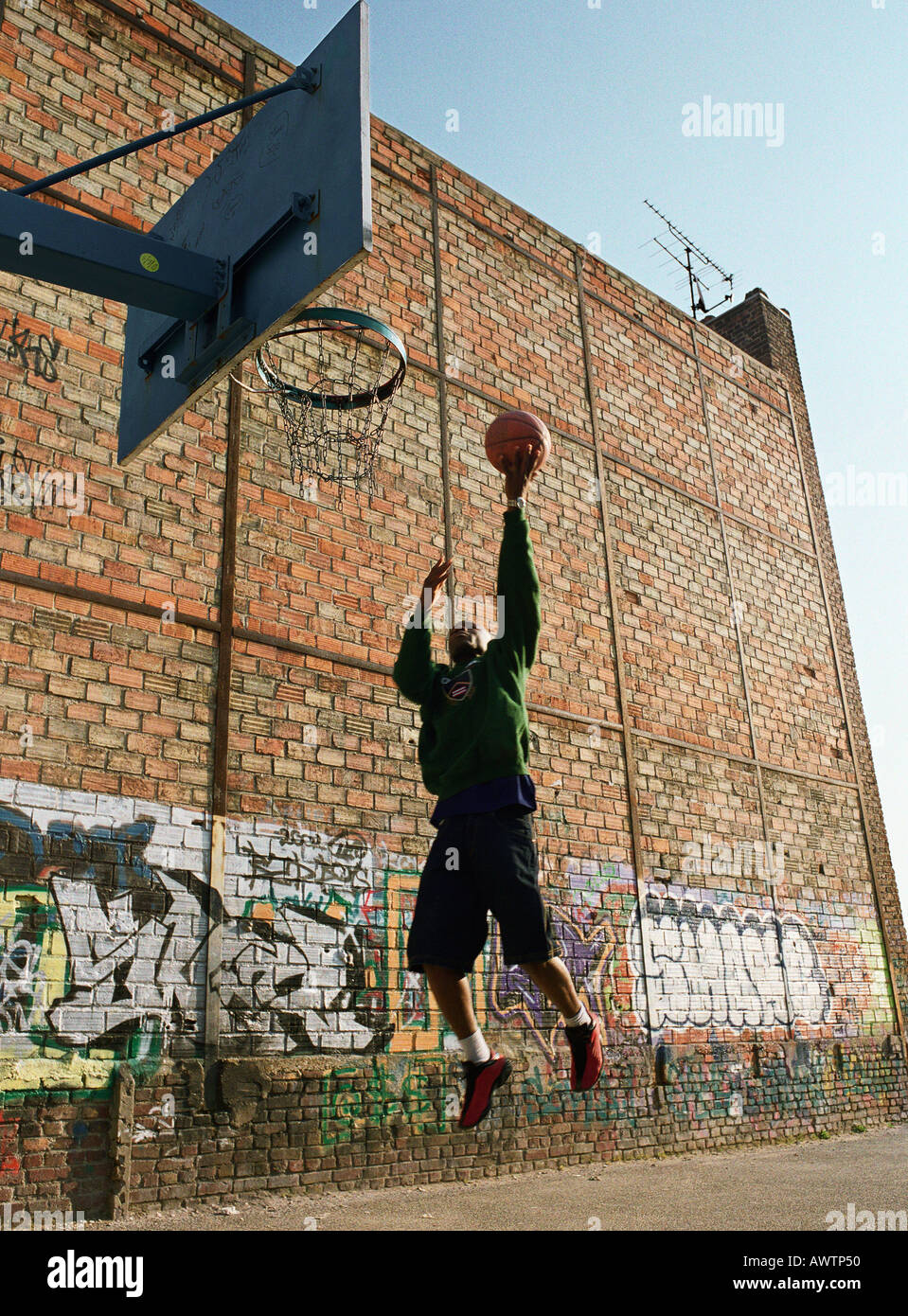 Mann geht für einen Basketball-Lay-up neben Graffitied Wand Stockfoto