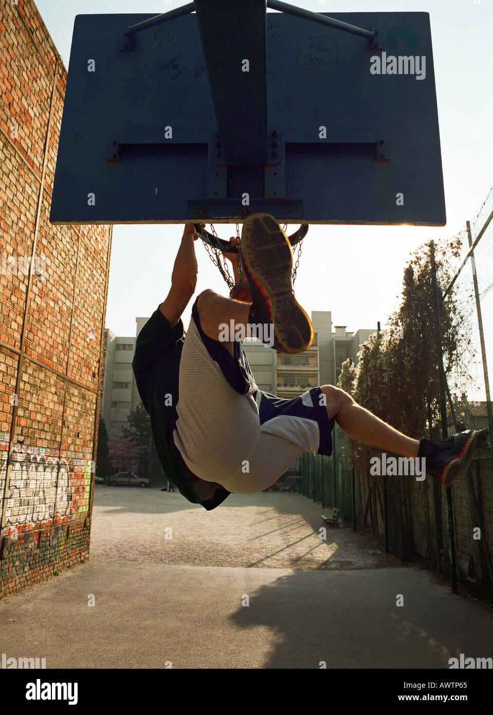 Man hängt an Basketball-Felge nach dunking Kugel, von hinten erschossen Stockfoto