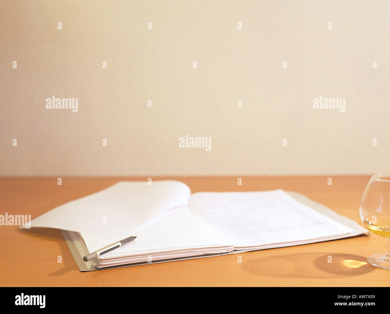 Offenes Buch auf Schreibtisch neben Glas und Stift Stockfoto