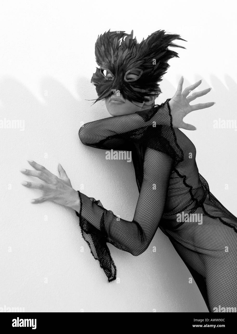 Monochromes Bild eines Mädchens in einem schwarzen Netz Kleid und schwarzen Feder Maske Stockfoto