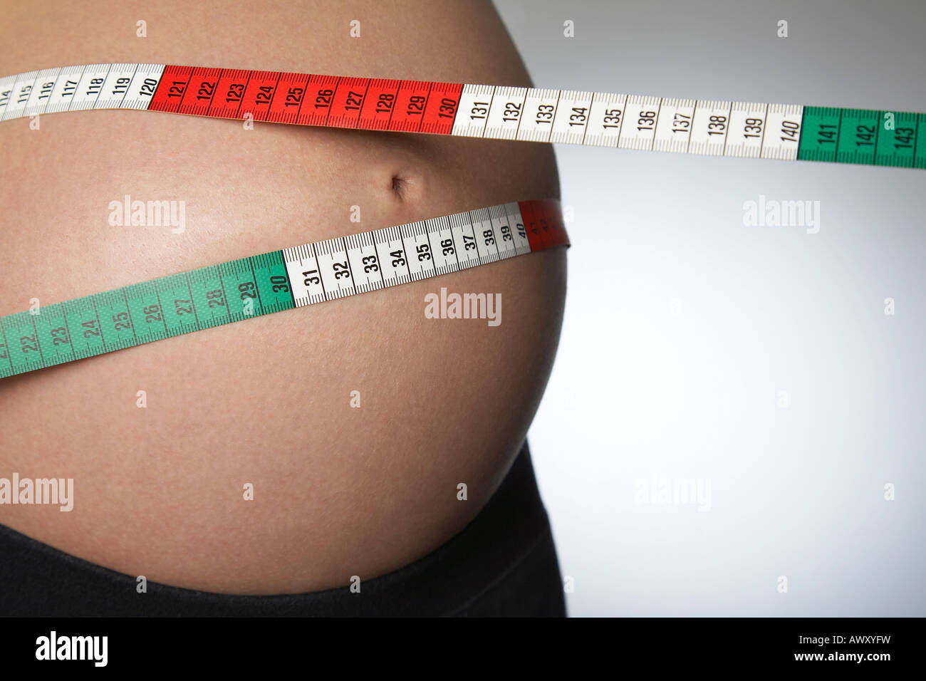 Schwangere Frau mit Maßband um Bauch, Mittelteil, Nahaufnahme, Studio gedreht Stockfoto