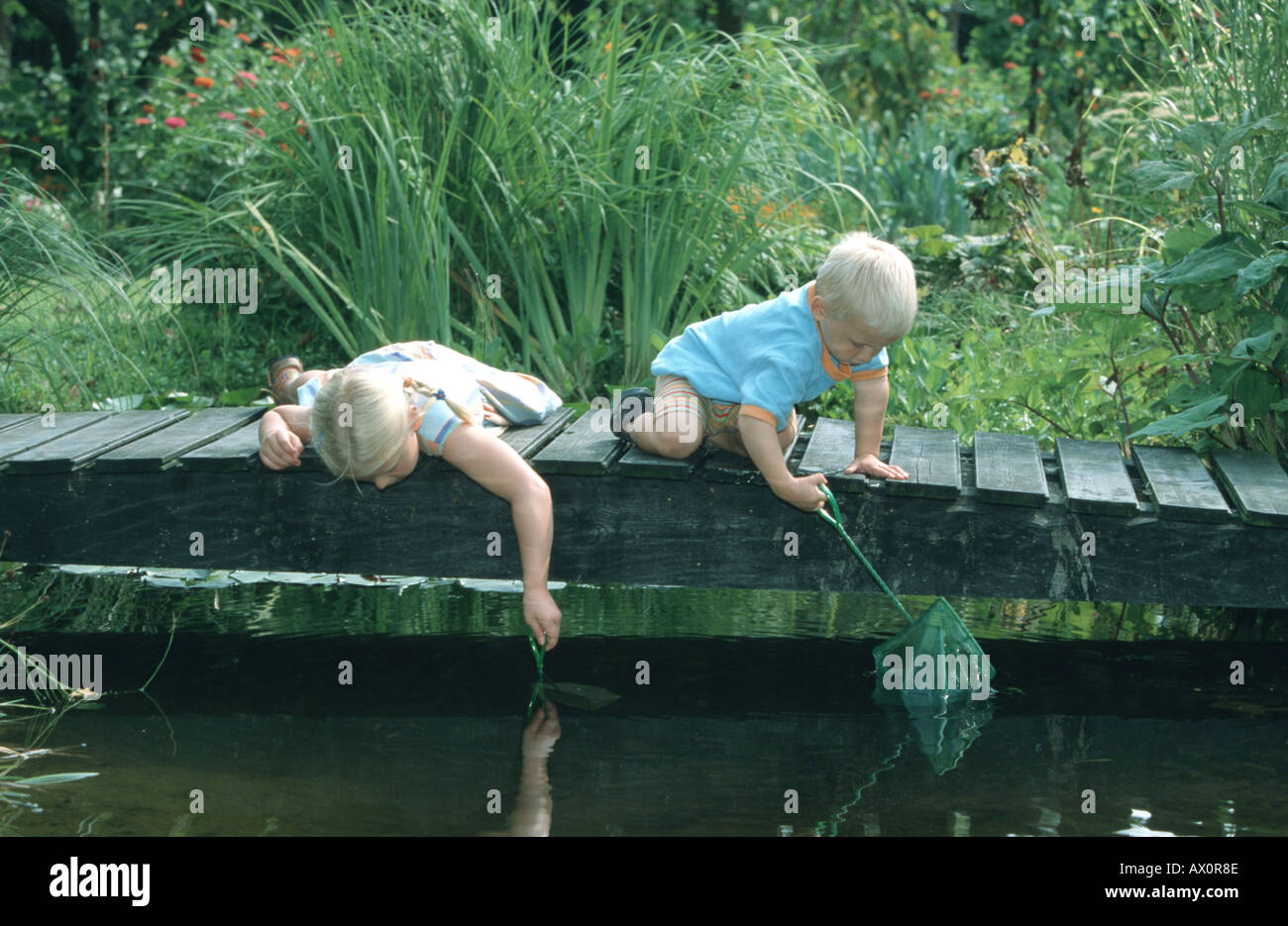 zwei spielende Kinder am Gartenteich, 3 Stockfoto