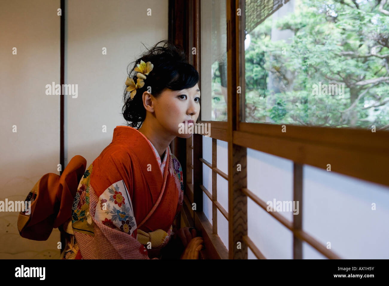 Eine Frau trägt einen Kimono und schauen aus dem Fenster Stockfoto