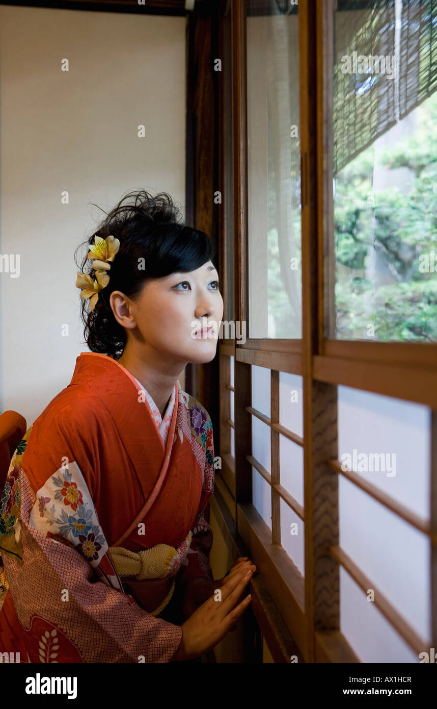 Eine Frau trägt einen Kimono Blick durch ein Fenster Stockfoto