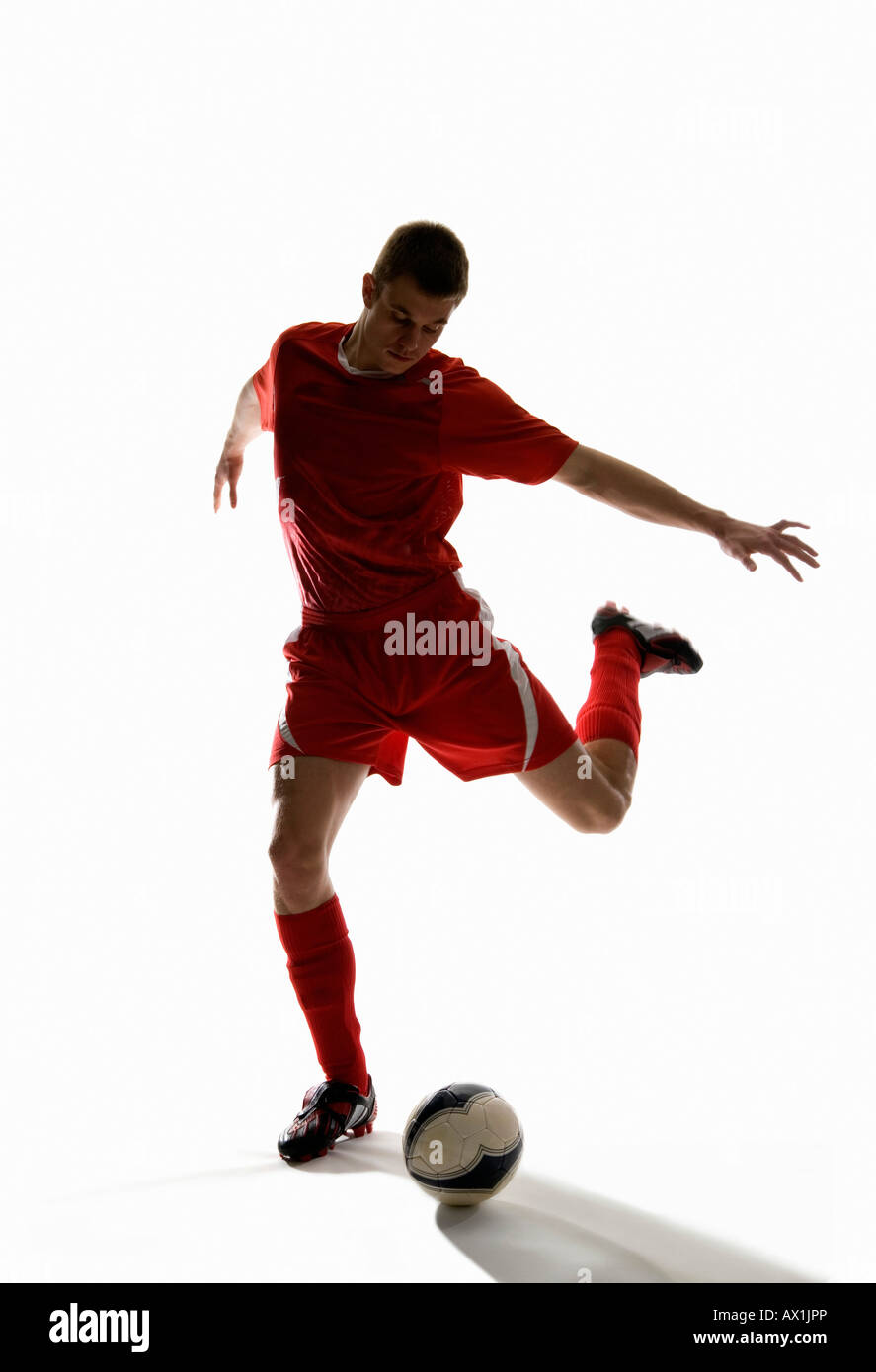 Studioaufnahme eines Fußballspielers treten einen Fußball Stockfoto