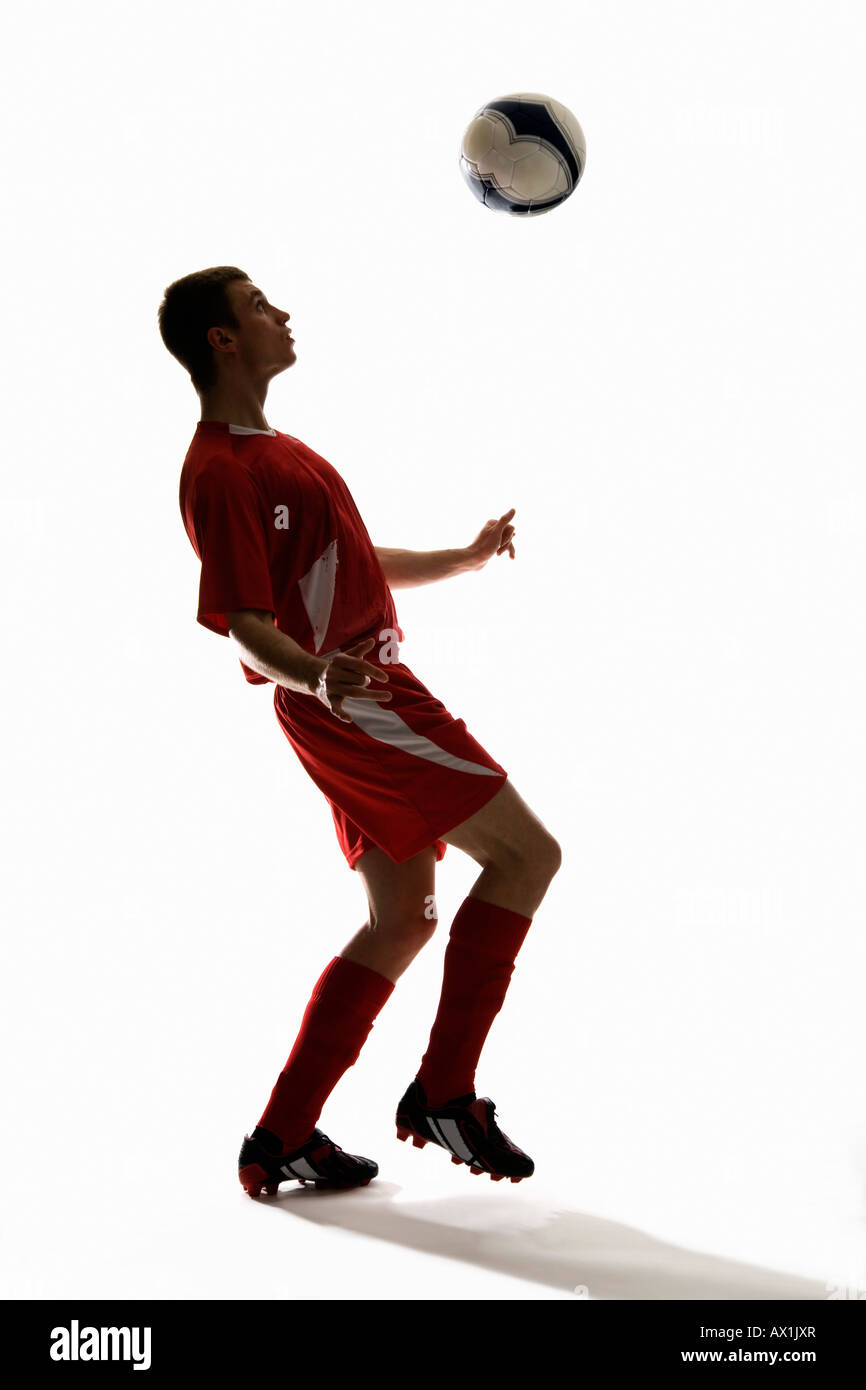Studioaufnahme eines Fußballspielers Prellen einen Fußball auf der Brust Stockfoto