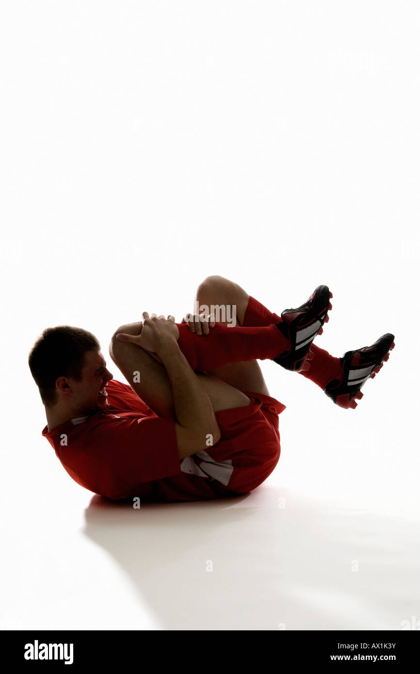 Studioaufnahme von einer verletzten Fußballspieler hält sein Bein Schmerzen Stockfoto