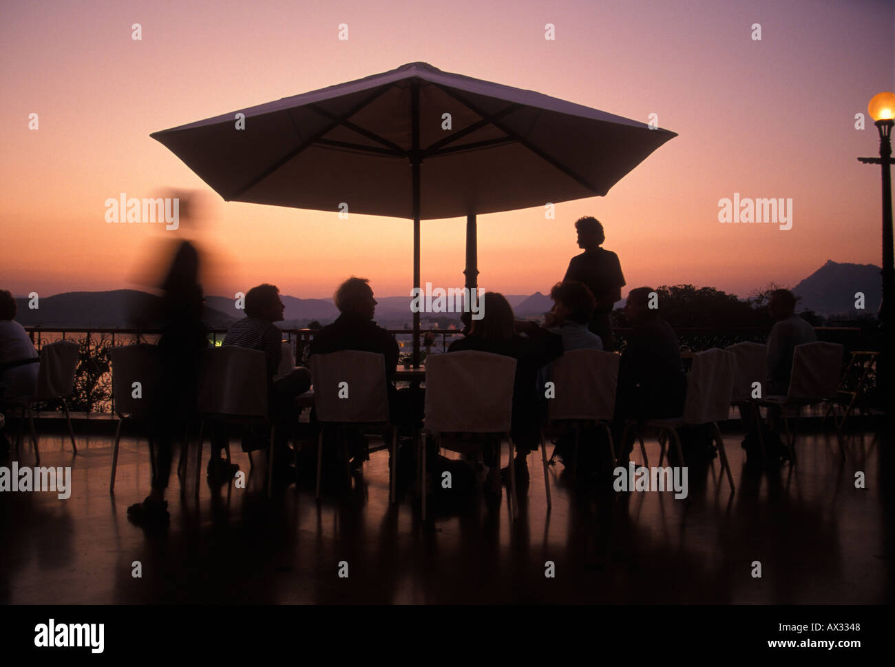 Touristen genießen Getränke auf das Sunset View Terrasse der Fateh Prakash Palace Hotel, während Sie den Sonnenuntergang über Lake Pichola-Udaipu Stockfoto