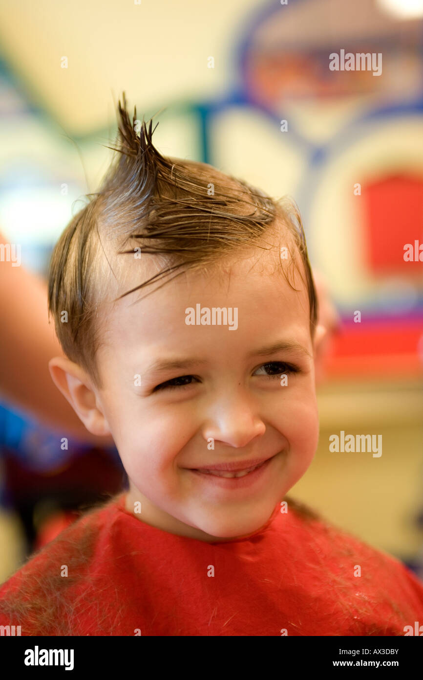 Ein lächelnder junge bekommt einen Haarschnitt Stockfoto