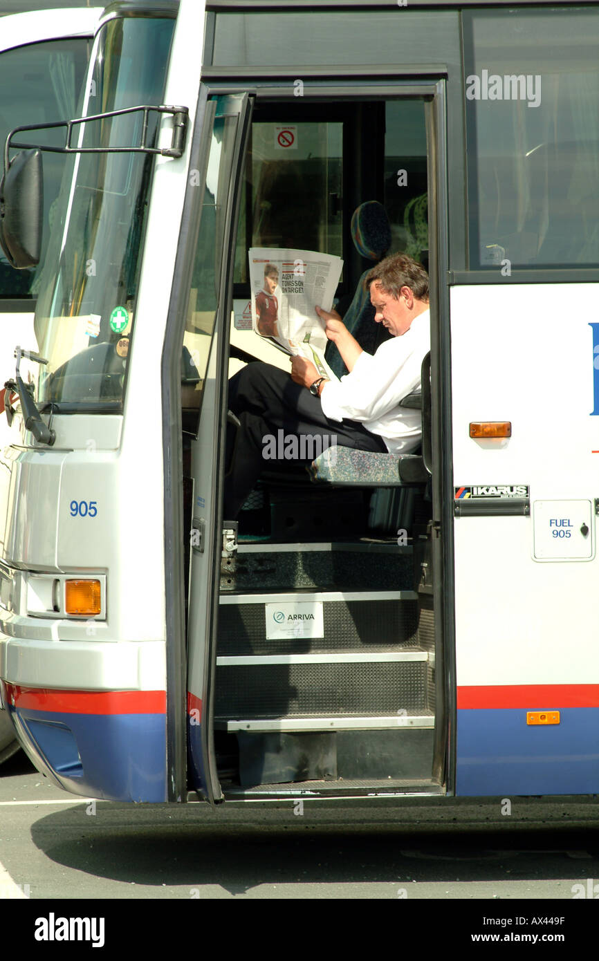 Busfahrer, die Zeitung lesen, während eine Ruhezeit Stockfoto