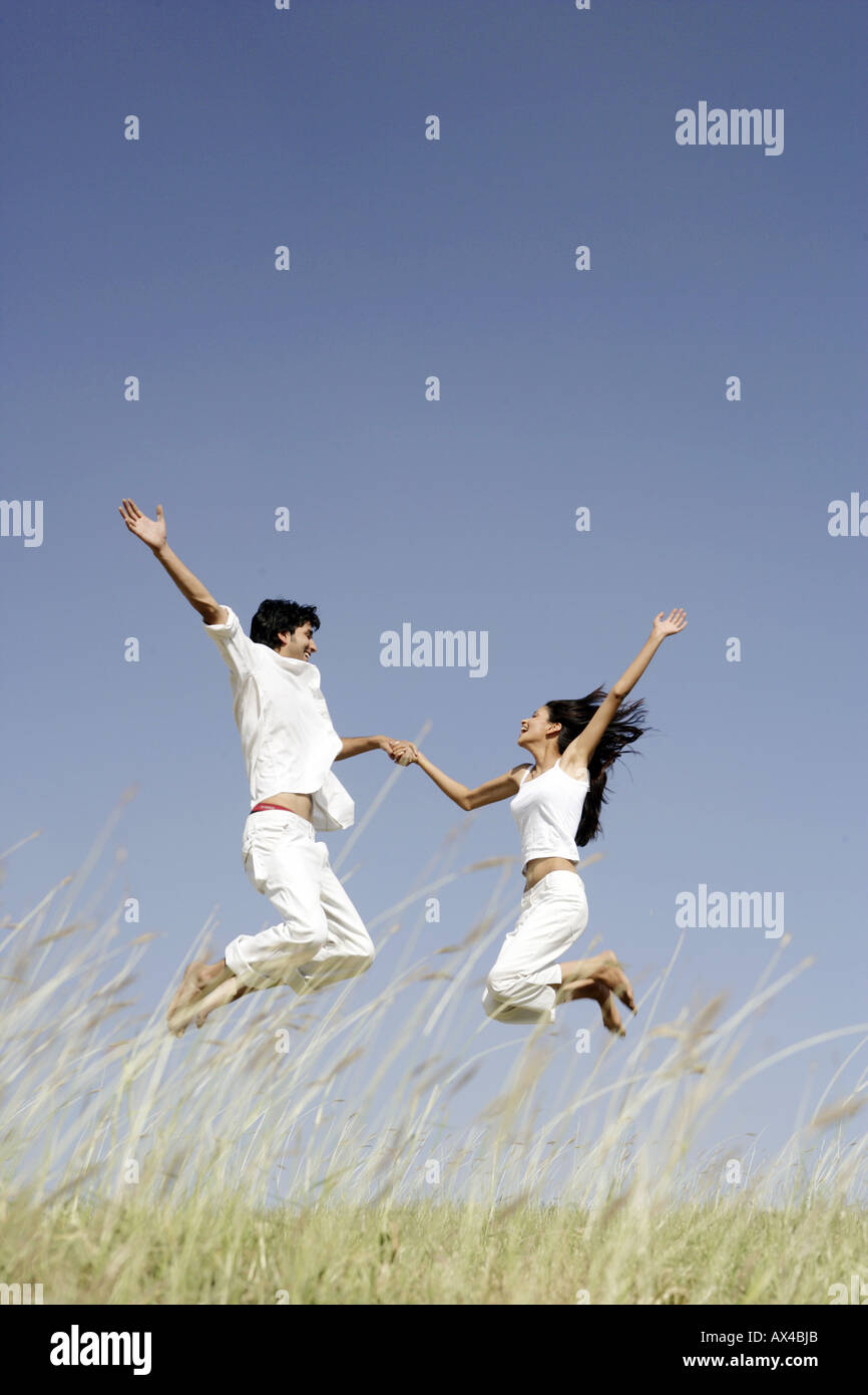 Seitenansicht eines jungen Paares in einem Park springen Stockfoto