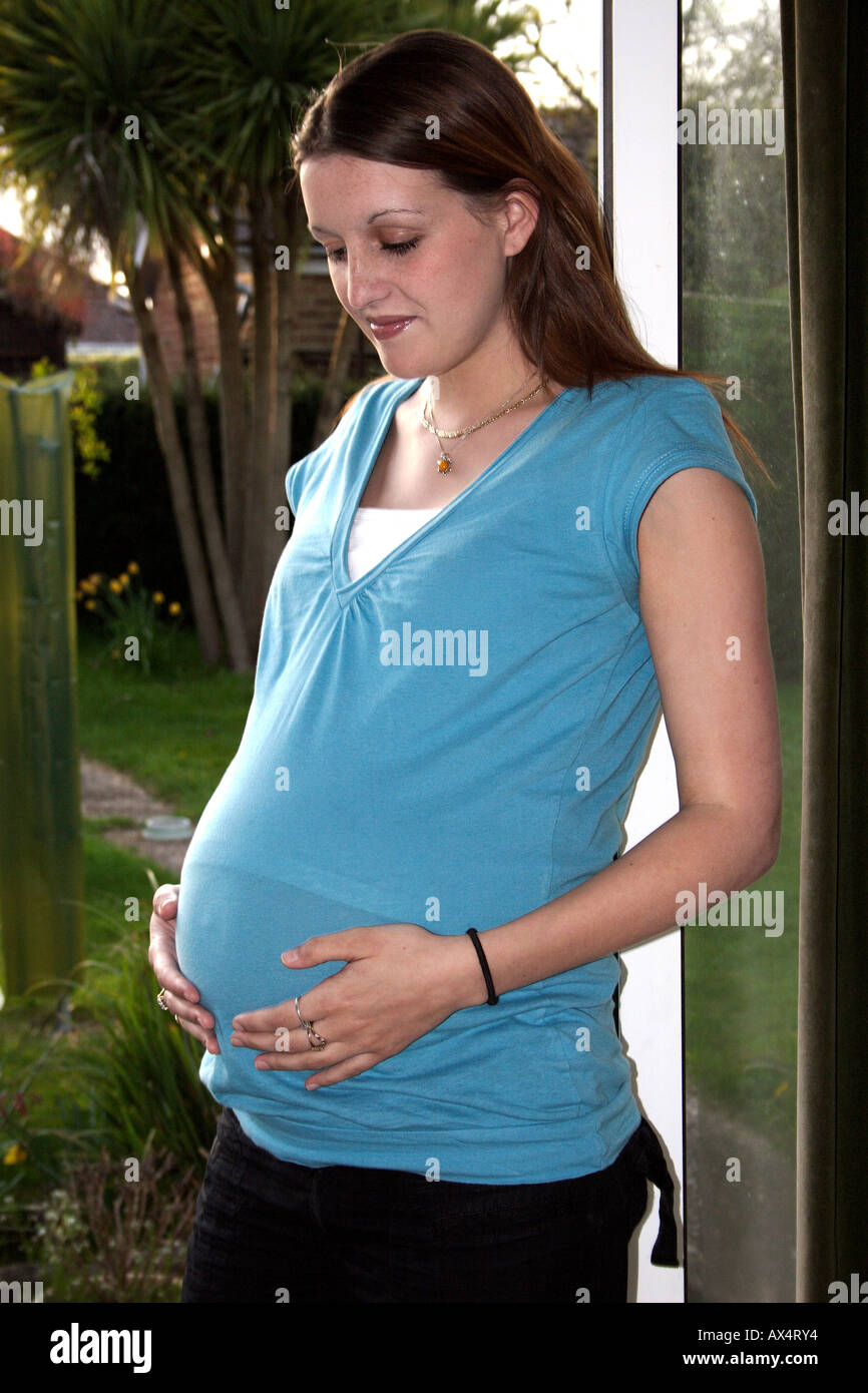 Junge hochschwangere Frau in offenen Tür blickte auf ihrem Bauch Stockfoto