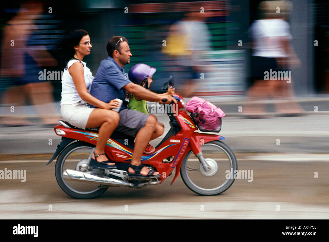 Ein Mann Frau und Kind auf einem Motorroller durch die Straßen von Ko Samui in Thailand. Stockfoto