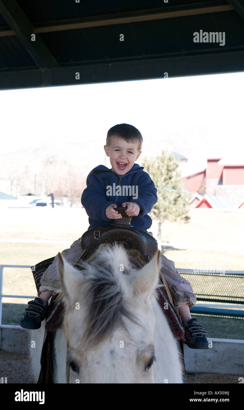 Ein kleiner Junge lächelt, während ein Ponyreiten Stockfoto