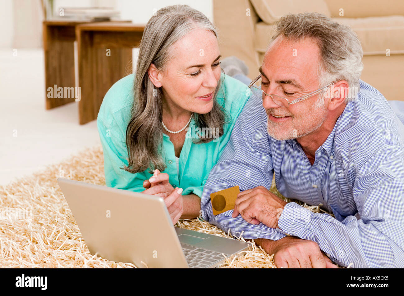 Älteres Paar auf Teppich liegend mit Laptop, Nahaufnahme Stockfoto