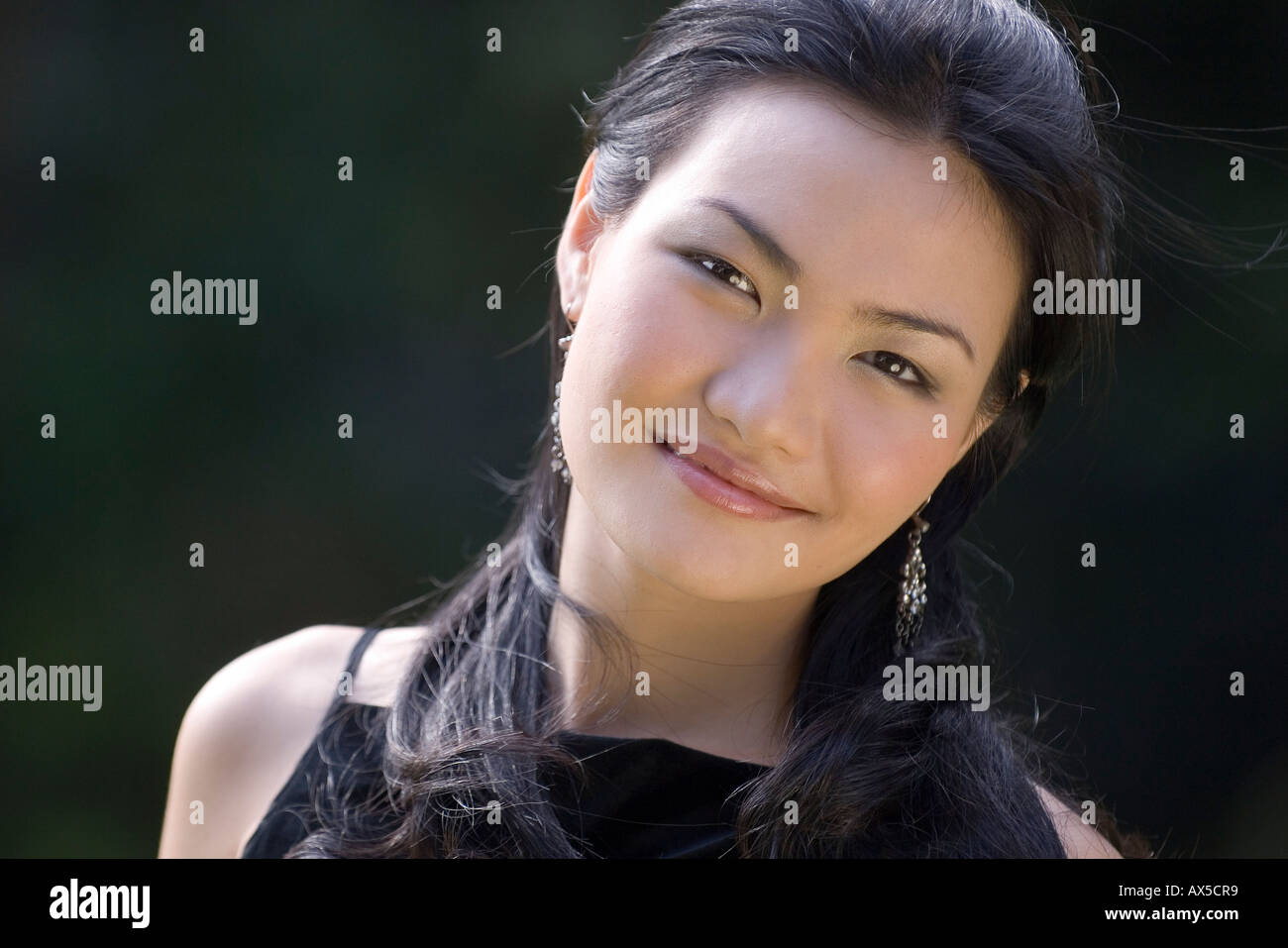 Eine schöne junge asiatische Frau posiert außerhalb in der untergehenden Sonne Stockfoto