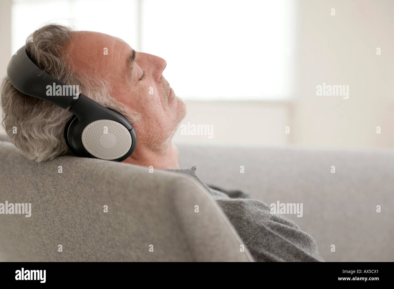 Reifer Mann mit Kopfhörern, Augen geschlossen, (Fokus auf Vordergrund) Stockfoto