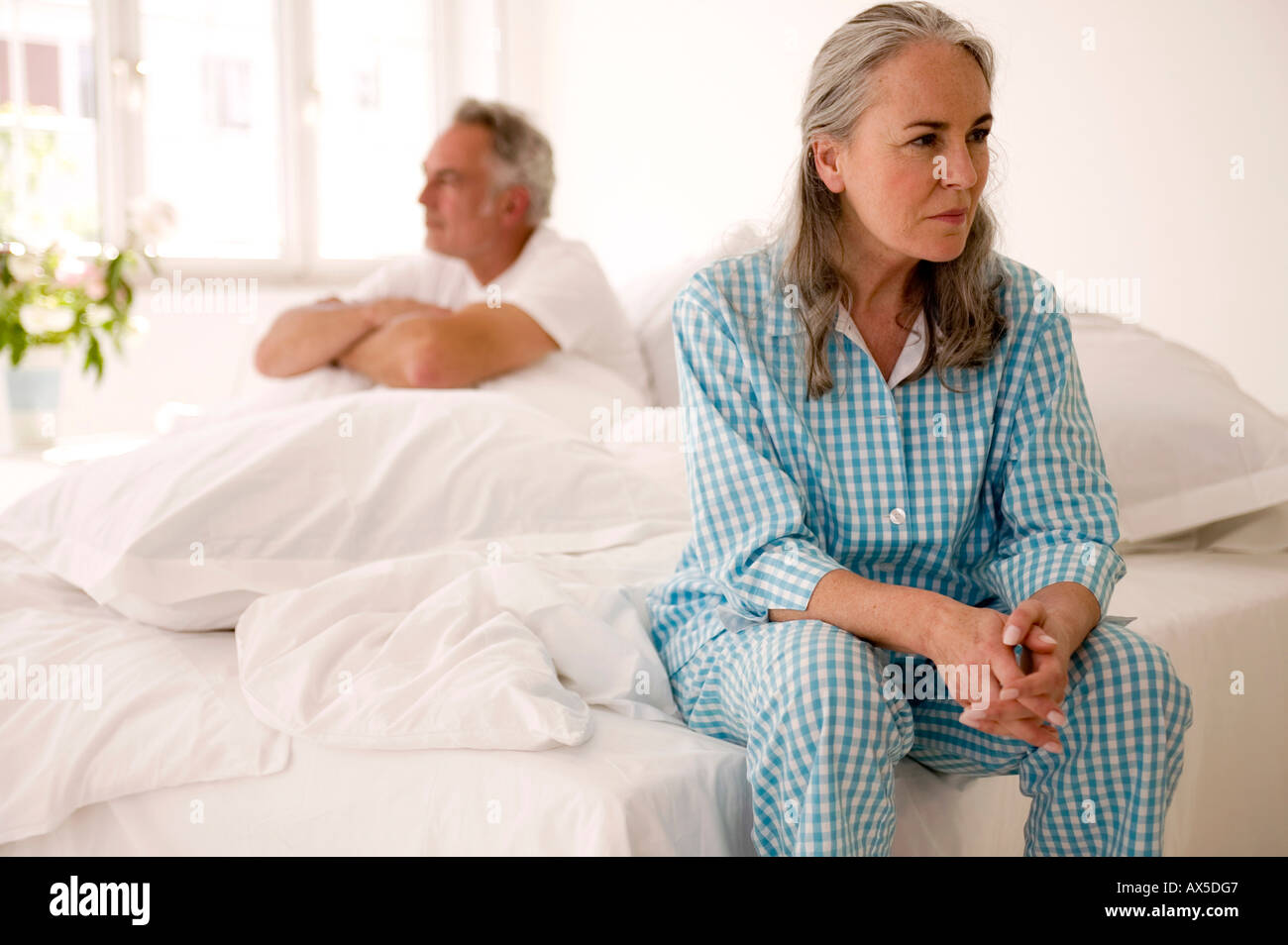 Älteres Paar sitzt auf Bett (Schwerpunkt: Frau im Vordergrund) Stockfoto