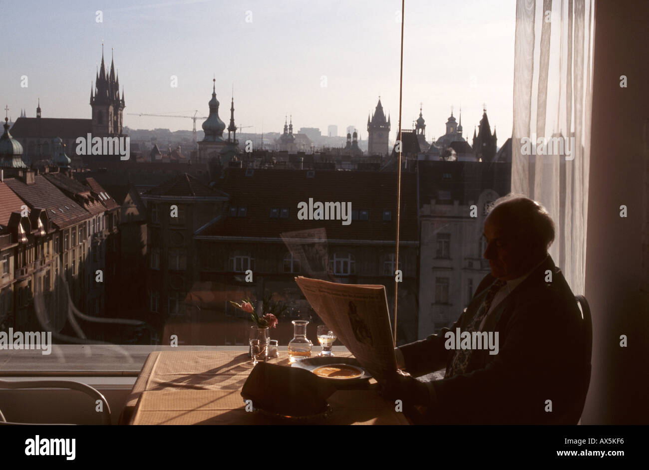 Prag, Tschechische Republik. Mann liest Zeitung im Restaurant auf der Dachterrasse mit Blick über die Altstadt. Stockfoto