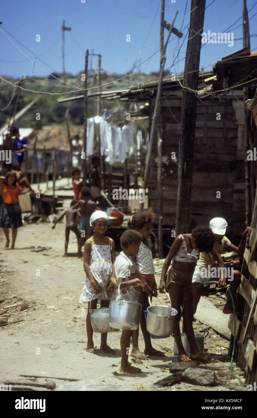 Salvador da Bahia, Brasilien. Favela Kinder Queueing, Wasser aus dem kommunalen Wasserhahn zu sammeln; Alagardos Favela, Bundesstaat Bahia. Stockfoto