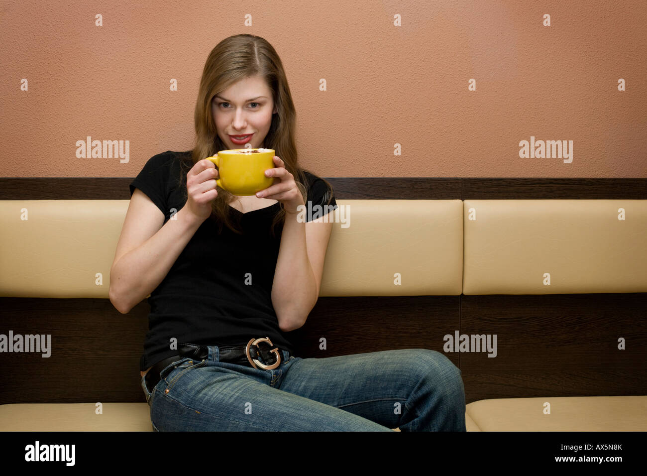 Junge Frau trinkt eine Tasse Latte in einer bar Stockfoto