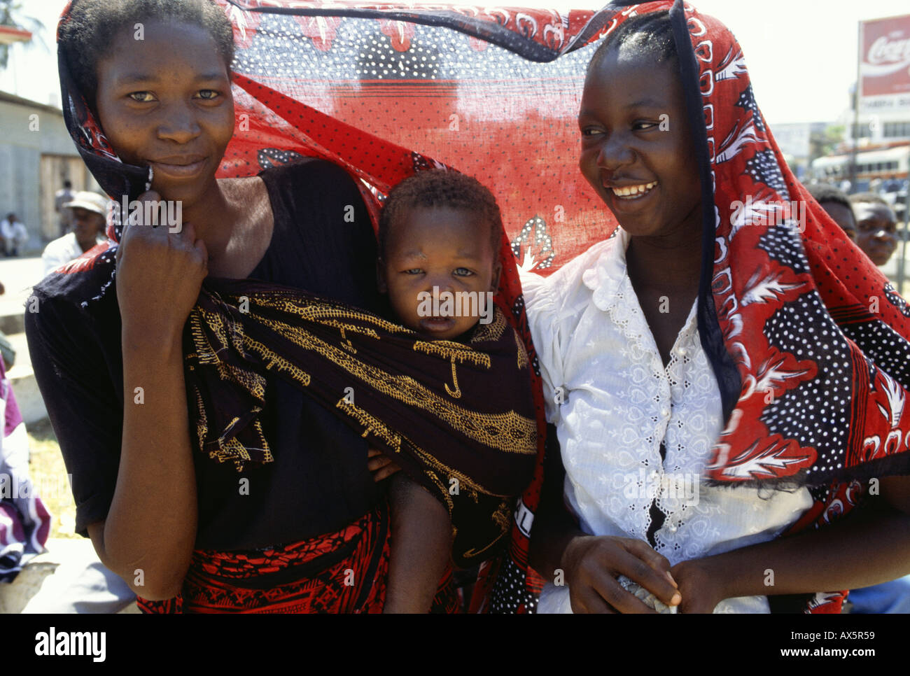 Tansania, Afrika. Frau mit Baby in einem hellen farbigen gedruckten Baumwolltuch gebunden. Stockfoto