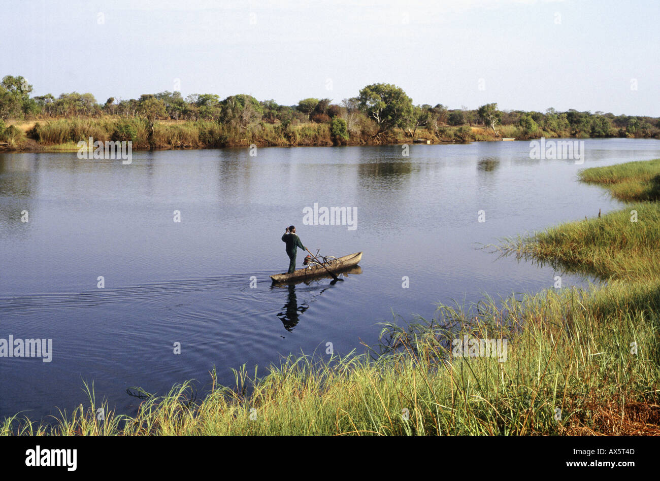 Sambia, Afrika. Ein Mann stehend in einem Einbaum-Kanu mit einem Fahrrad auf dem Fluss von See Chaya, gonna Kabinga. Stockfoto