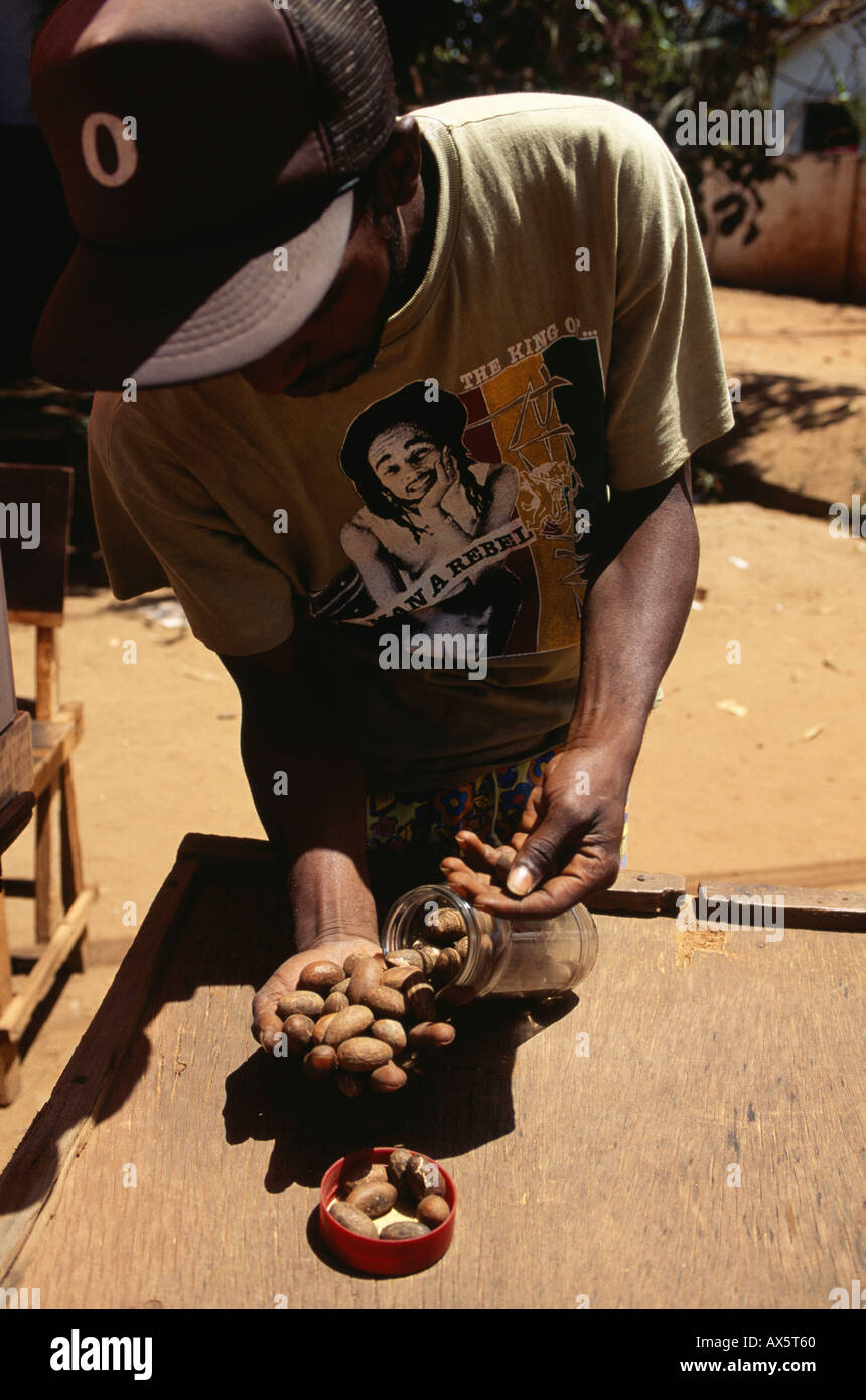 Gambia. Markt-Händler verkaufen Kolanüsse aus einem Glas; Boss Hut, Rasta T-shirt. Stockfoto