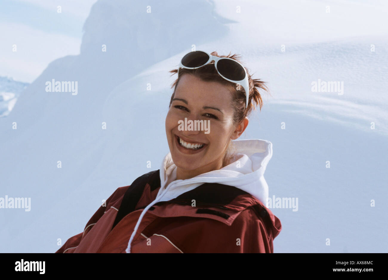 Junge Frau sitzt im Schnee, lächelnd, Nahaufnahme Stockfoto