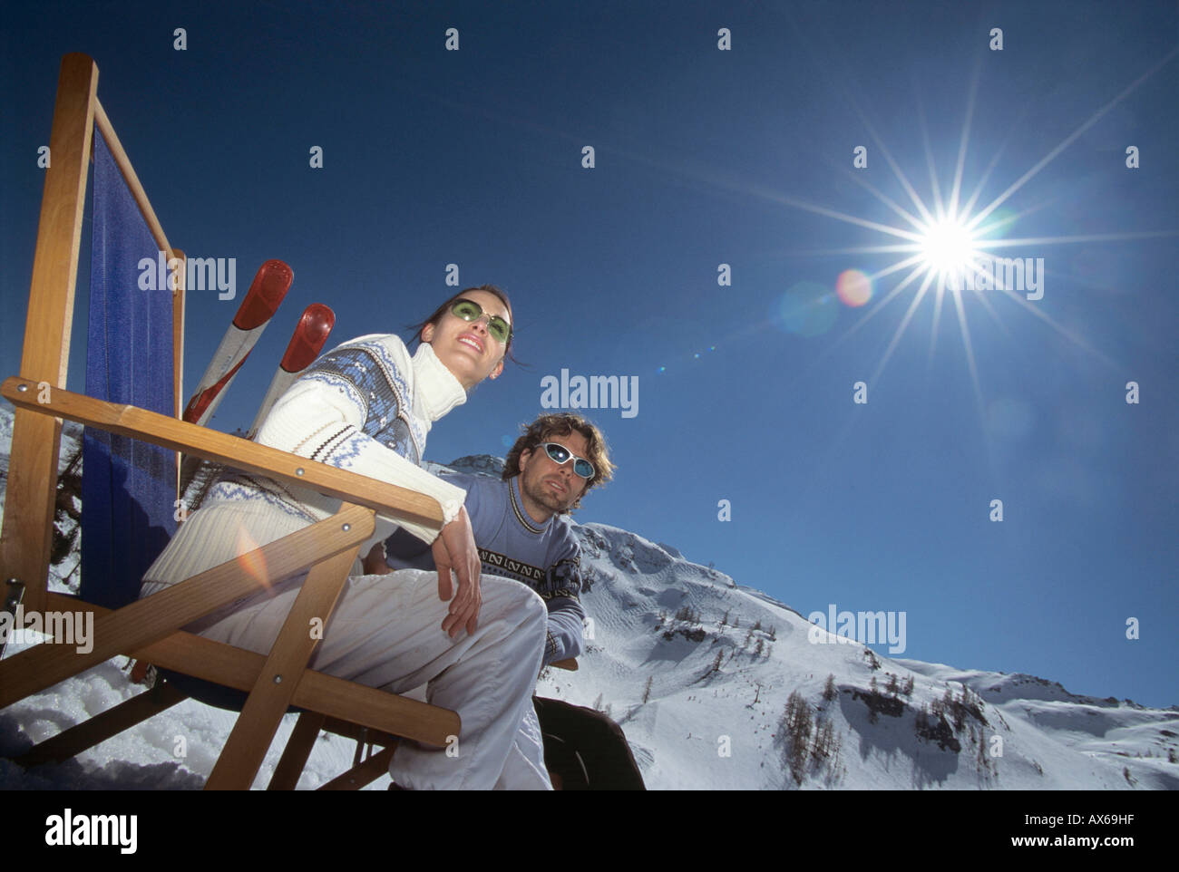 Paar sitzt auf Liegestühlen im Schnee, niedrigen Winkel Ansicht Stockfoto