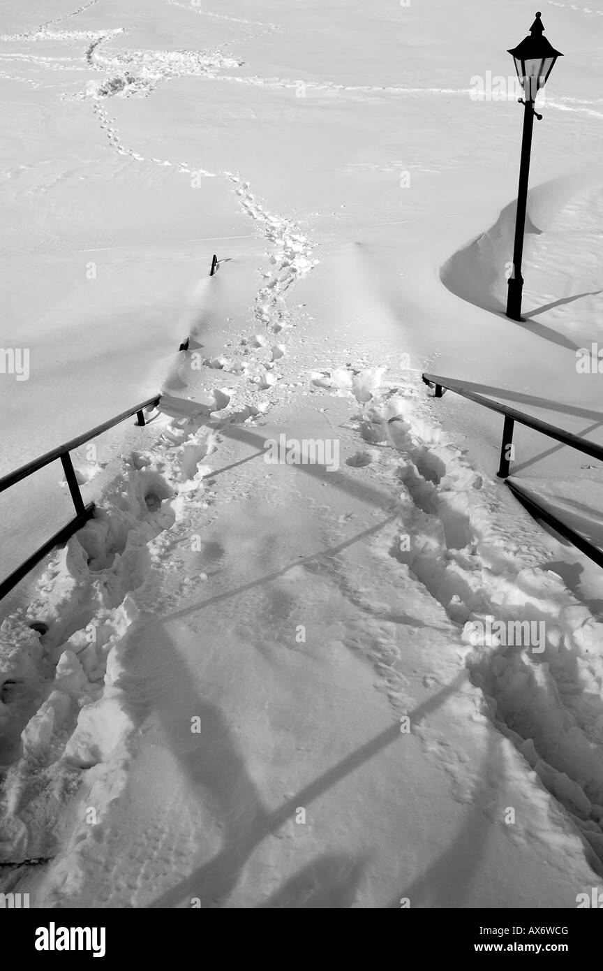 Eine Spur von Fußspuren führen auf einer schneebedeckten Straße Stockfoto