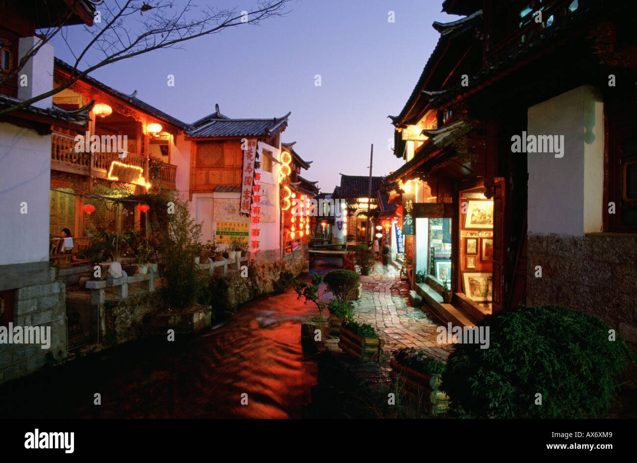 Geschäfte und Restaurants entlang einem Stein gepflasterten Straße in Lijiang in der Nacht, Lampions von den Geschäften hängen Stockfoto