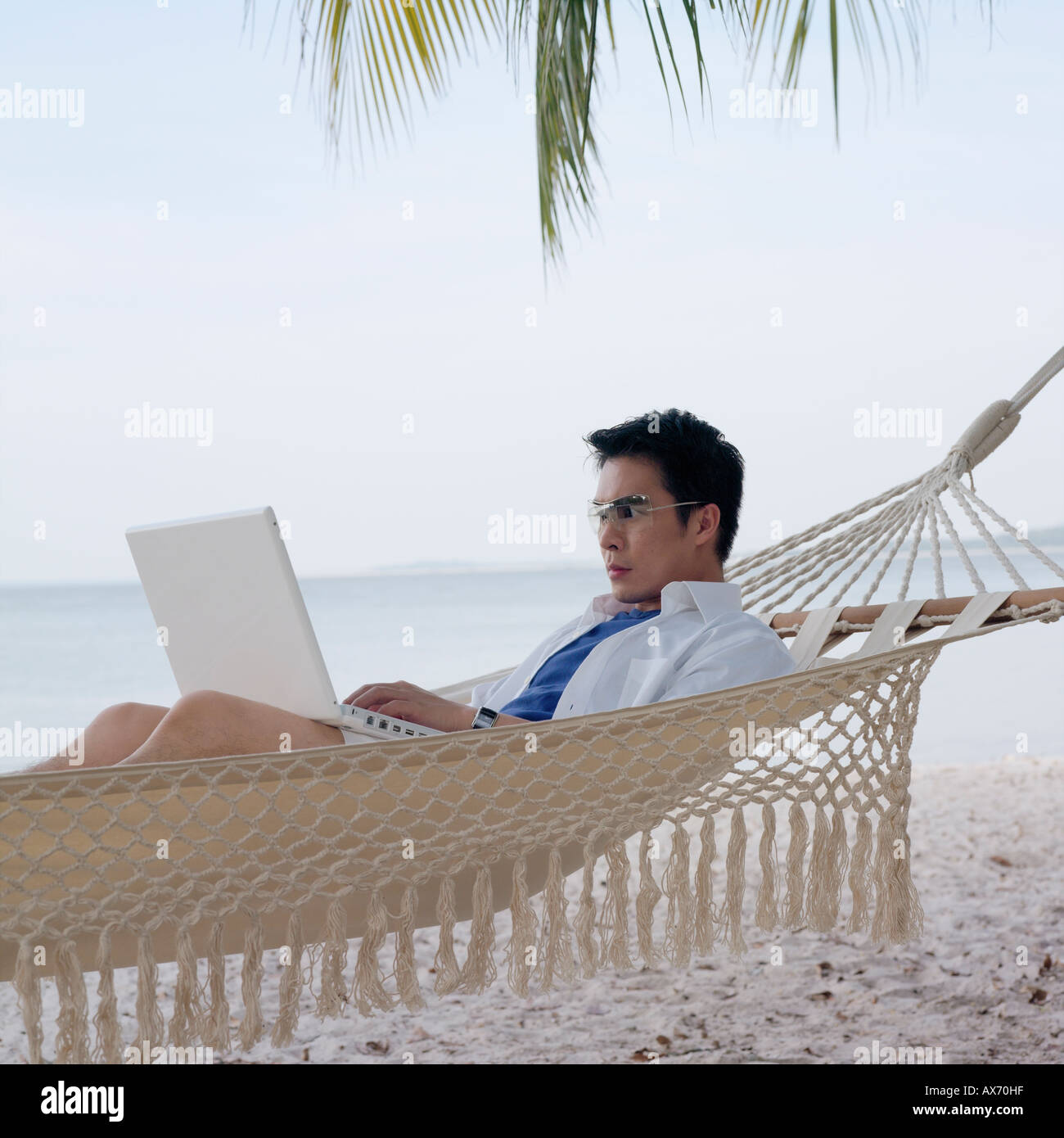 Seitenansicht eines Mitte erwachsenen Mannes liegen in der Hängematte mit einem laptop Stockfoto