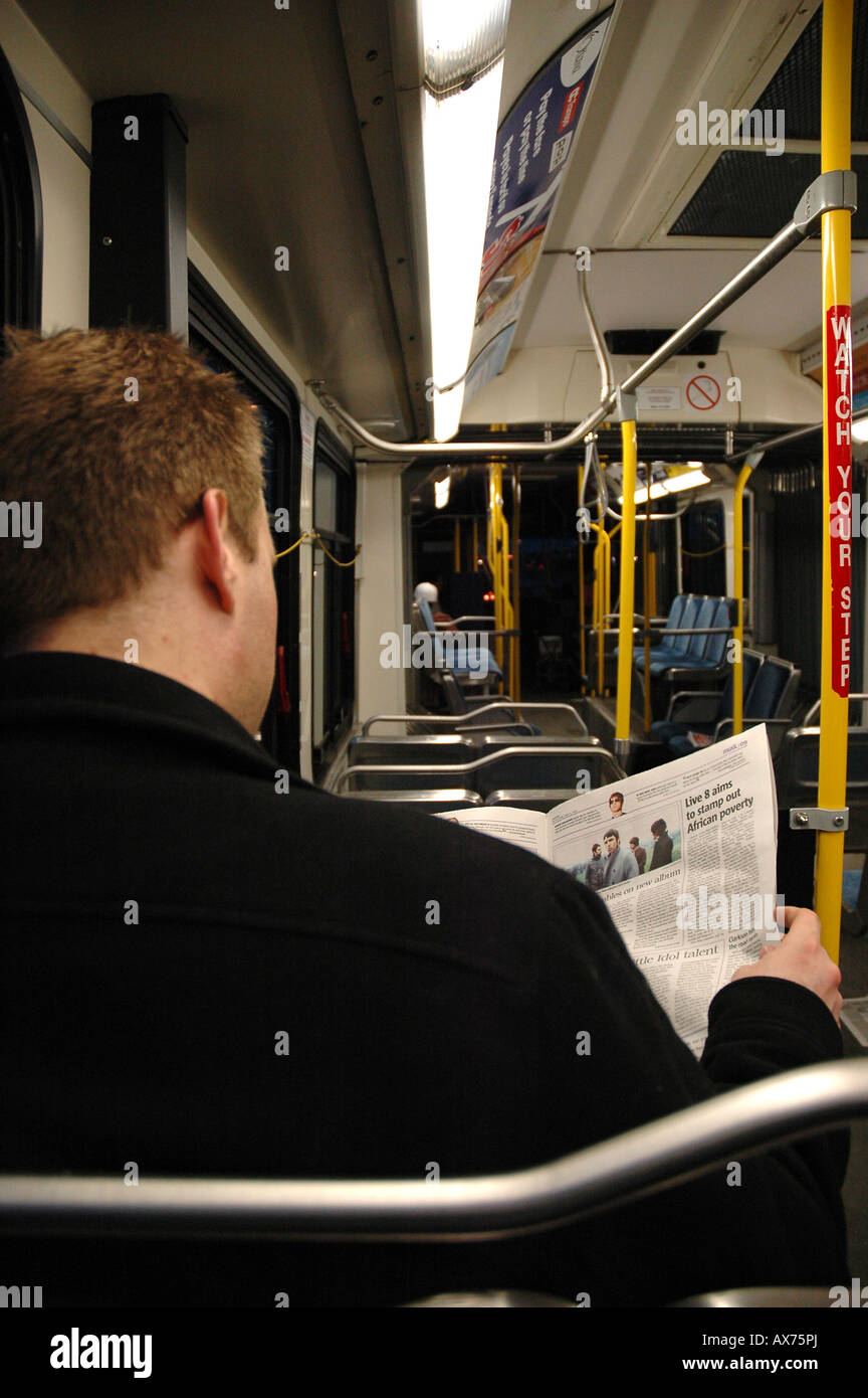 Ein Bus-Passagier hält sich mit einer Zeitung beschäftigt Stockfoto