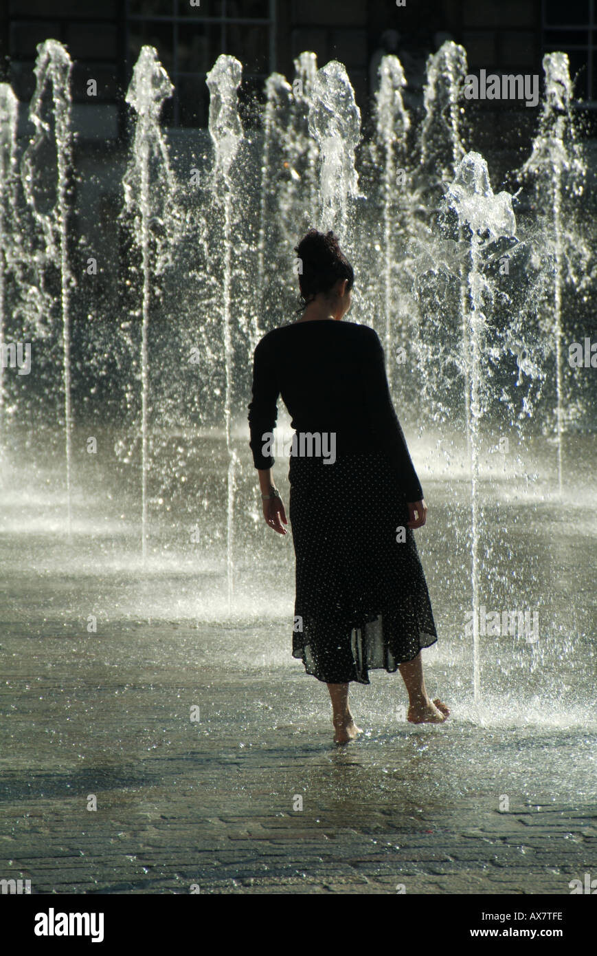 Sommer-Springbrunnen-Wasser-Spiel junge Frau kühlt sich von heißem Sommer-Wetter-Konzept testen das Wasser oder Tauchen Zehen im Wasser London England Großbritannien Stockfoto