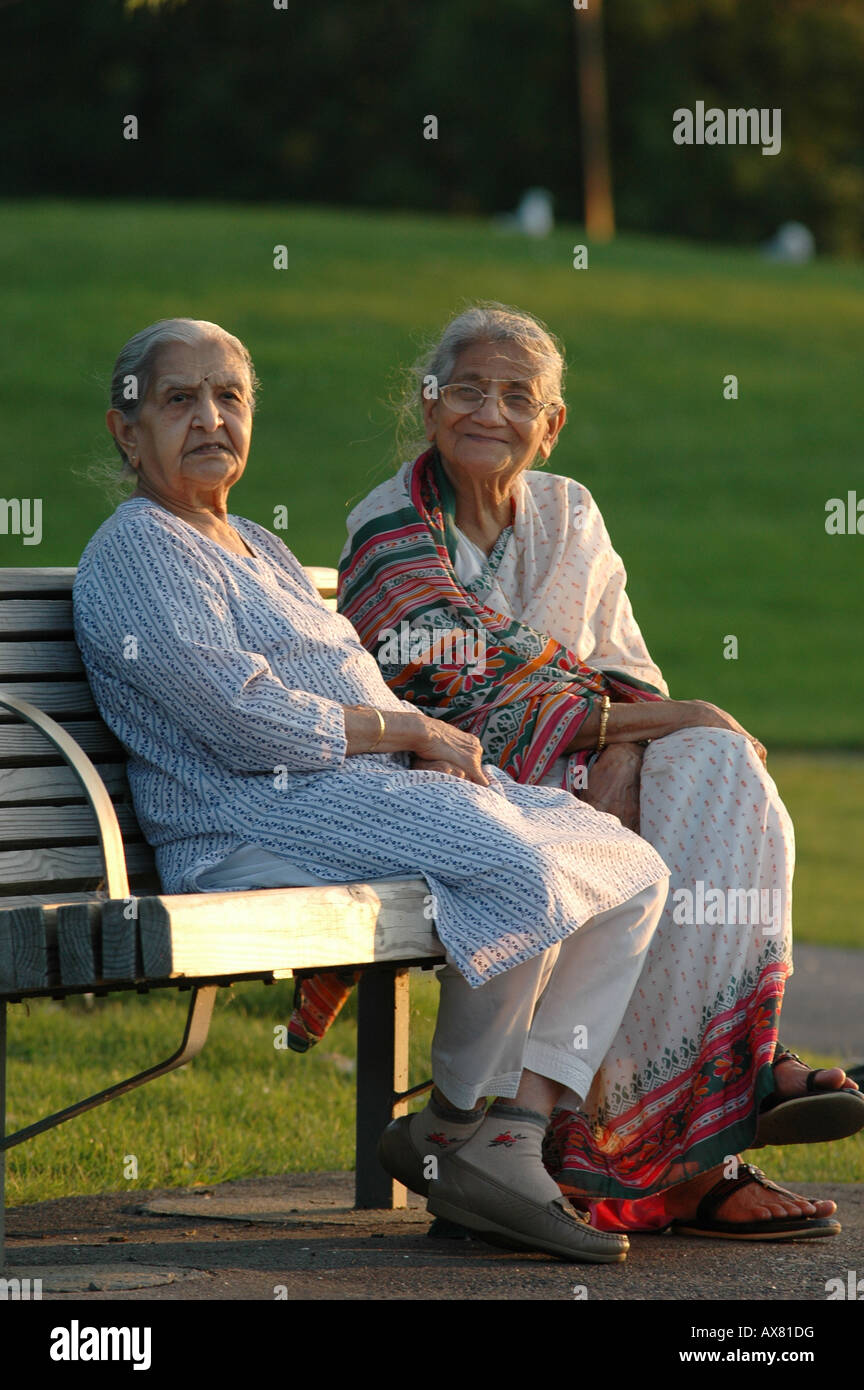 Ein paar ältere indische Frauen sitzen zusammen auf einer Parkbank Stockfoto