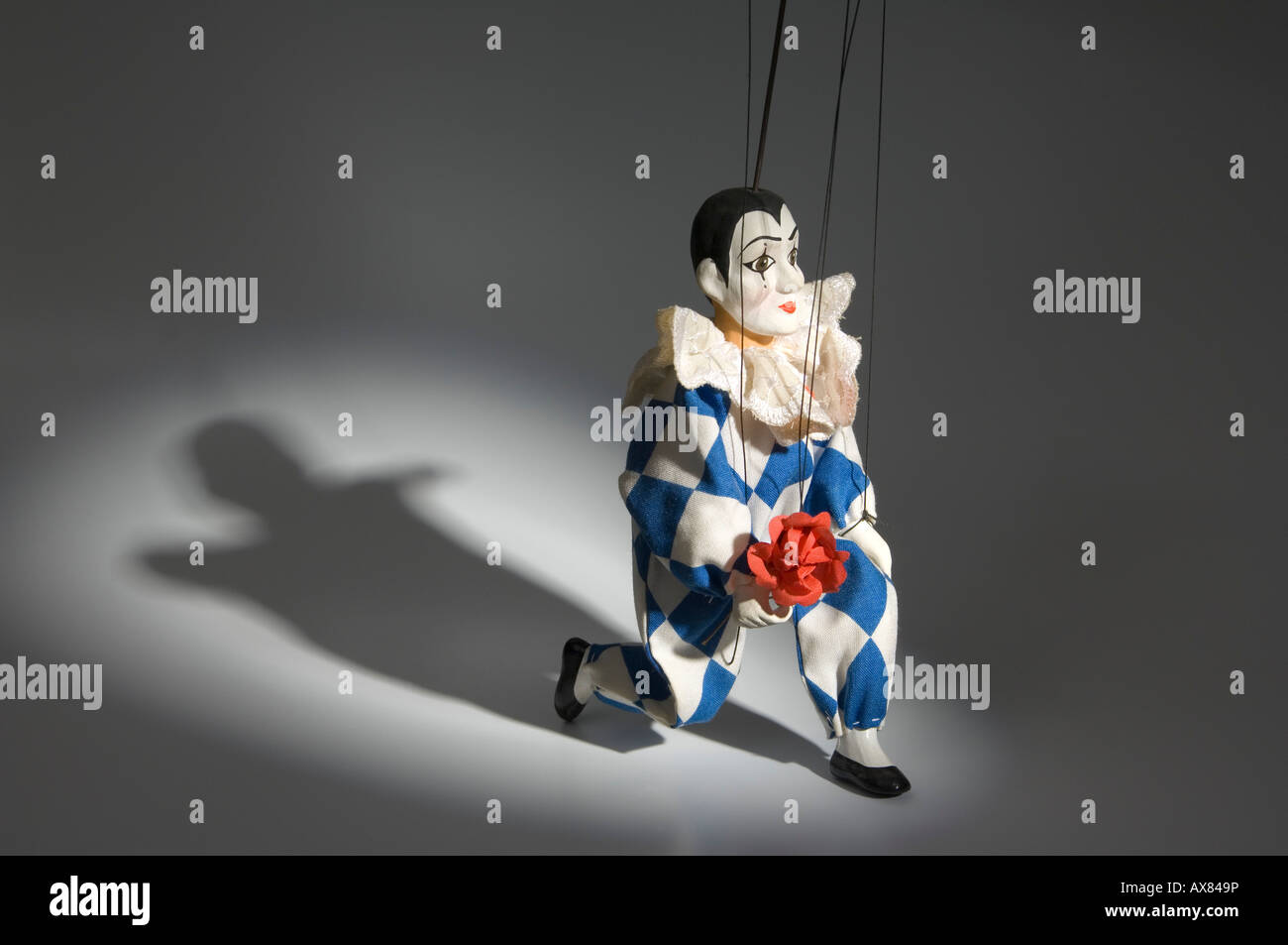 Eine Marionette des Pierrot Clown bietet eine Rose im Rampenlicht Stockfoto