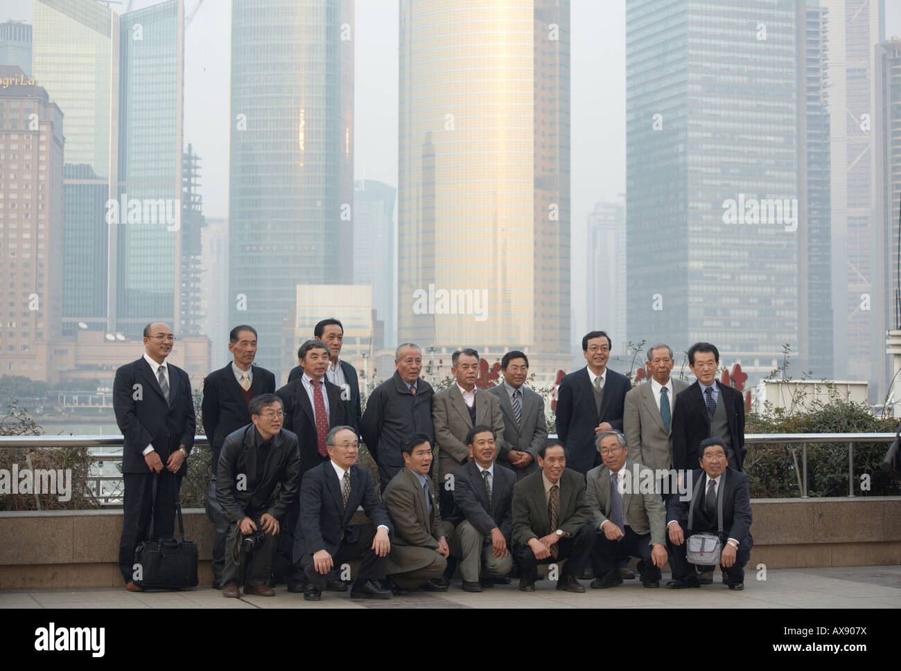 Japanische Geschäftsleute posieren für ein Gruppenfoto am Bund mit Geschäftsviertel Pudong in Shanghai China im Hintergrund Stockfoto