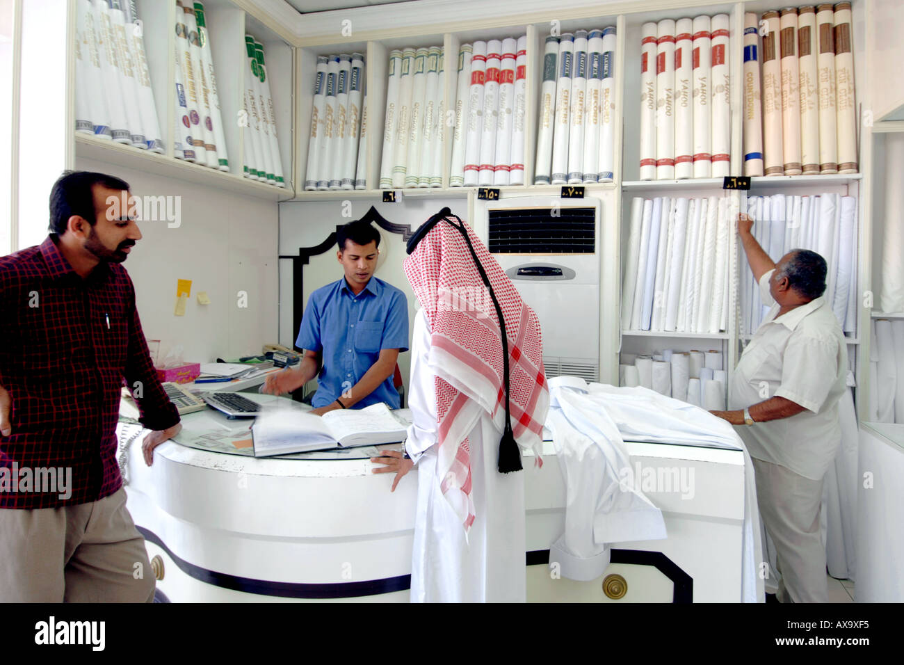 Ein arabischer Mann befiehlt ein neues Outfit von einem Stoff-Händler in Doha, Katar. Stockfoto