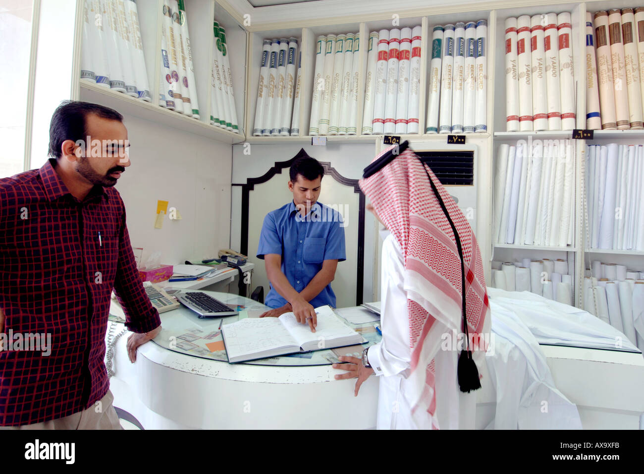Ein arabischer Mann befiehlt ein neues Outfit von einem Stoff-Händler in Doha, Katar. Stockfoto
