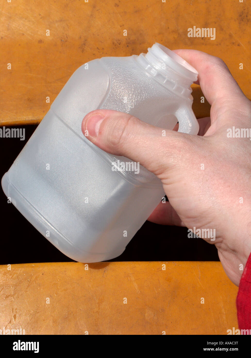 Mans Hand Platzierung einer recycelbaren leer undurchsichtig Pint Milch Kunststoff-Flasche in einen Papierkorb zur Wiederverwertung depot Stockfoto