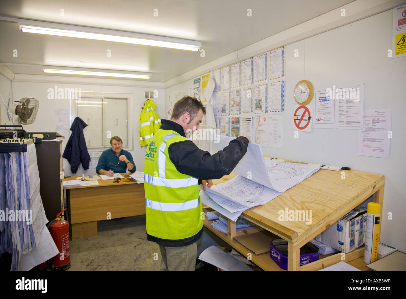 Elektro-Ingenieur betrachtet man Pläne im Baubüro Stockfoto