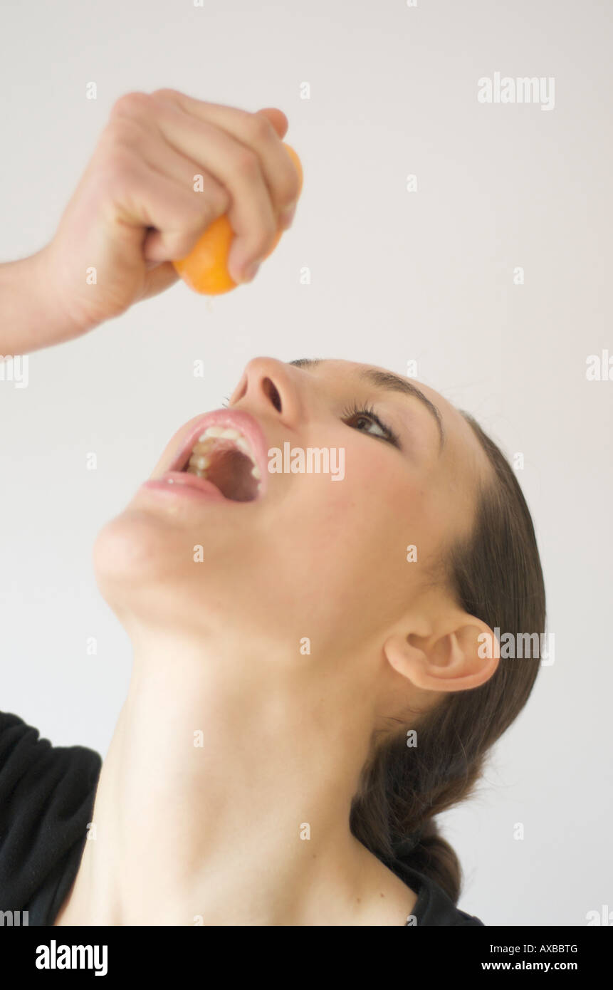 Junge gesunde Frau trinkt frisch gepressten Orangensaft Stockfoto