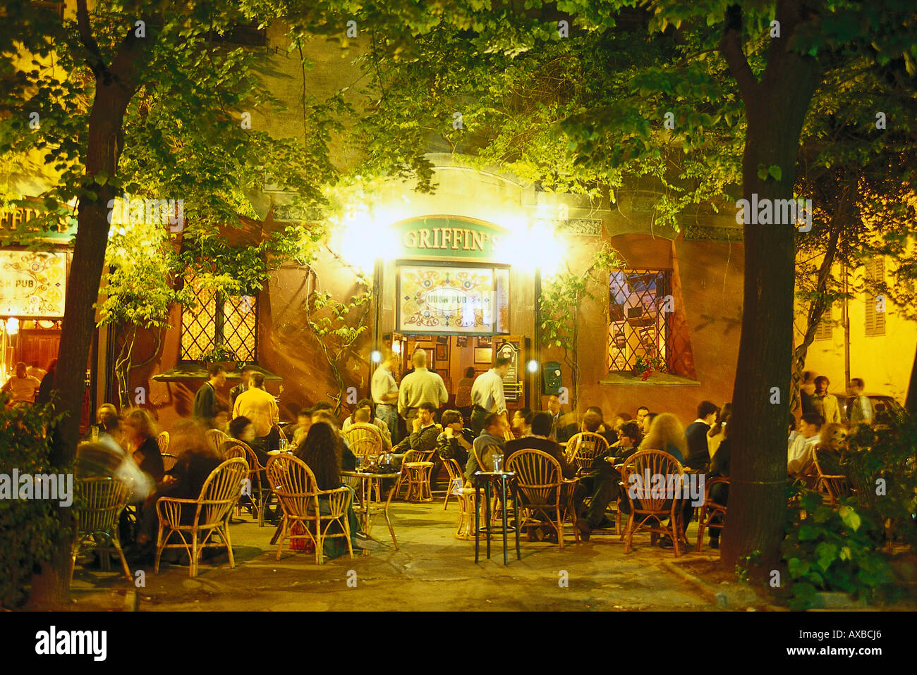 Menschen sitzen vor Griffin´s Pub unter Bäumen in den Abend, Largo Square, Modena, Emilia Romagna, Italien, Europa Stockfoto