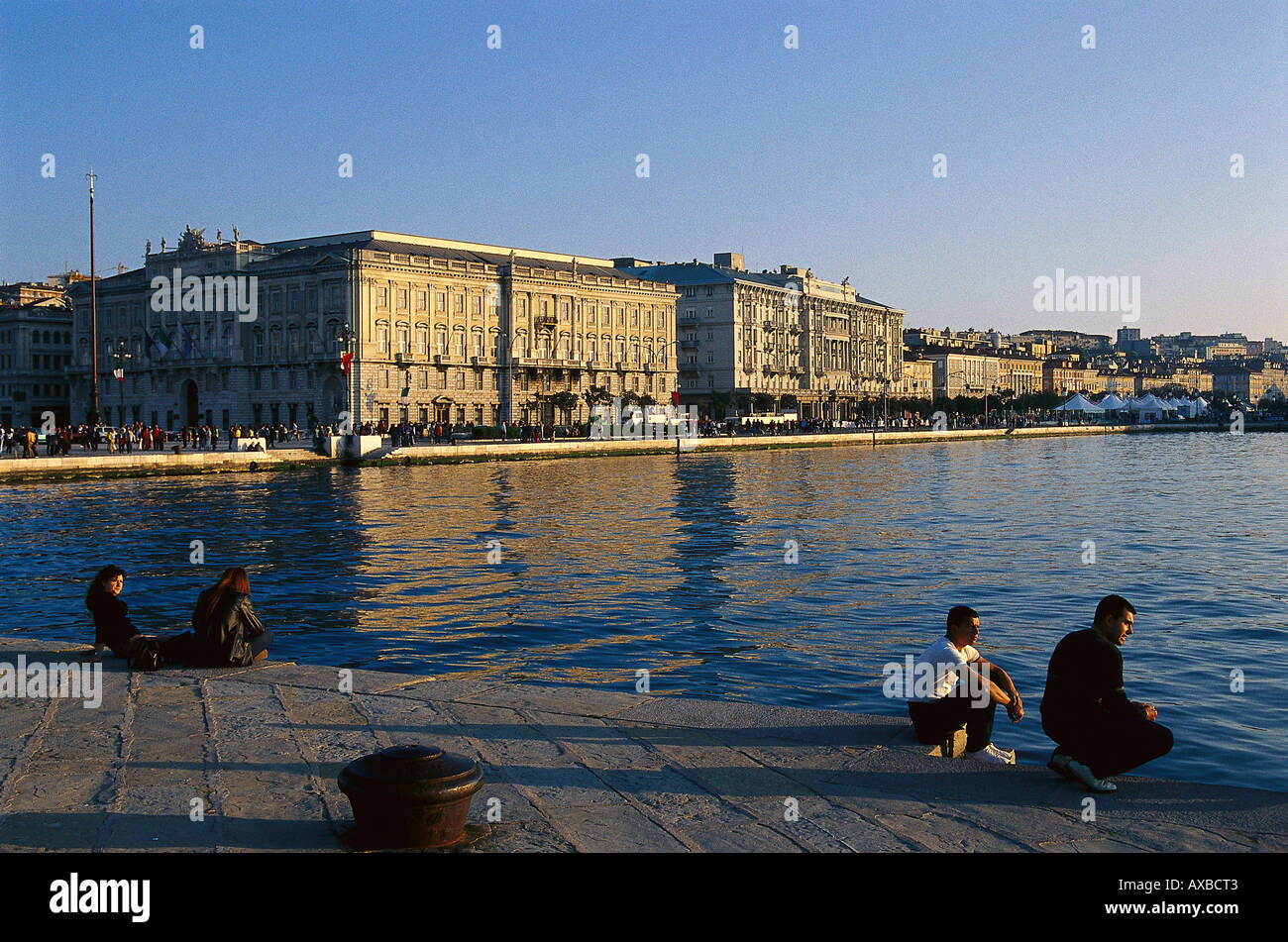 Leute sitzen auf dem Pier in den Abend Sonne, Mola Audace, Triest, Friaul, Italien, Europa Stockfoto