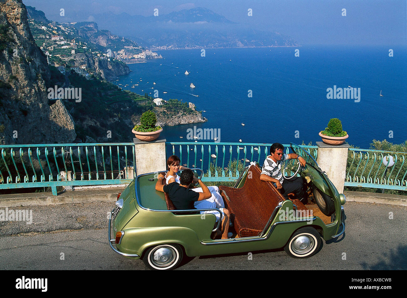 Menschen in einem Oldtimer an der Küste im Sonnenlicht, Amalfiküste, Kampanien, Italien, Europa Stockfoto