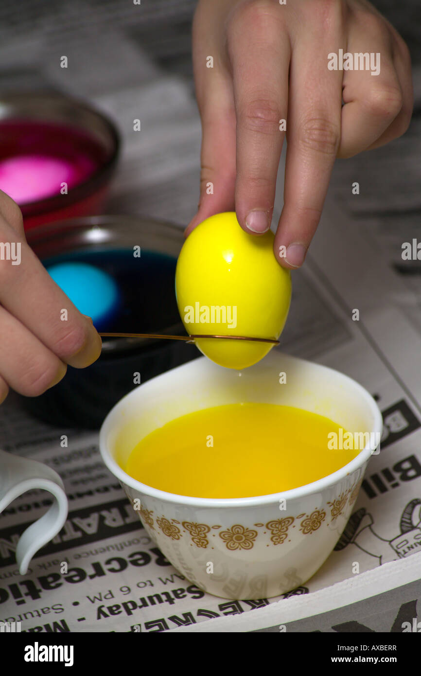 Ostereier in den Prozess der für Ostern gefärbt wird. Junges Kind zieht gelbes Ei aus der Farbstoff. Stockfoto